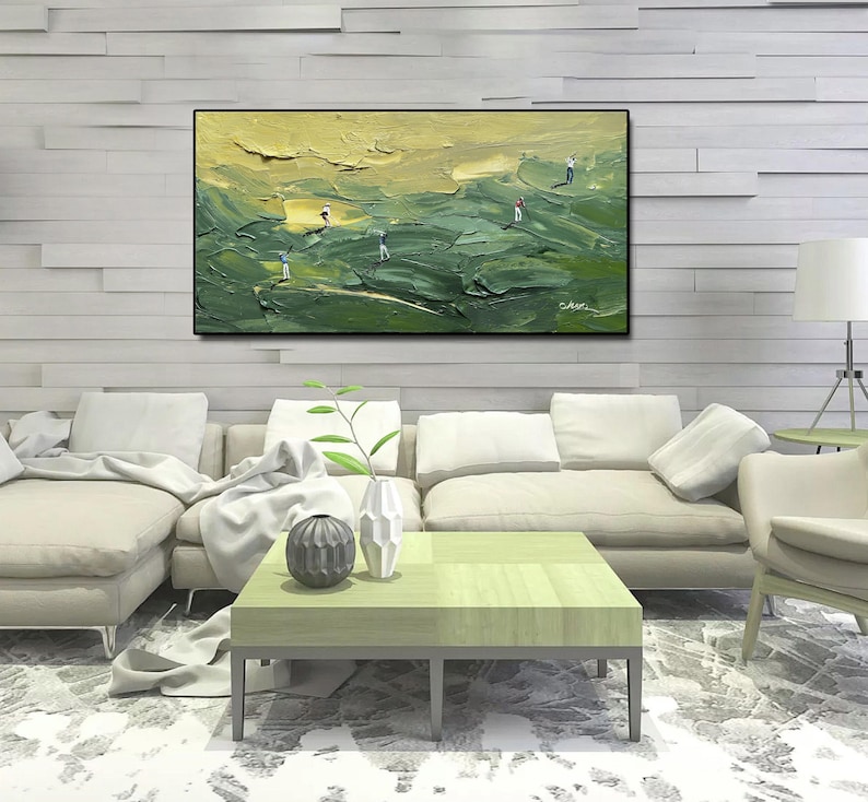 Op de afbeelding: Een olieverfschilderij van een golfbaan met golfers. Het kunstwerk heeft een textuur, impasto-stijl met tinten groen en geel. Het schilderij is zwart omlijst en hangt boven een moderne woonkamer.
