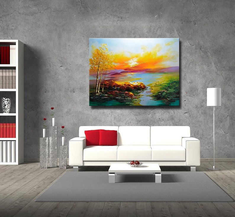 K&ouml;nnte beinhalten: Ein Gem&auml;lde, das eine Landschaft mit einem See, B&auml;umen und einem Sonnenuntergang zeigt. Das Gem&auml;lde befindet sich in einem Wohnzimmer mit einer wei&szlig;en Couch, einem Couchtisch und einer Stehlampe.