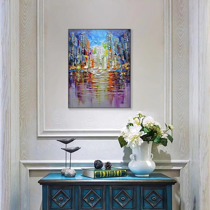Puede incluir: Una pintura abstracta colorida de un horizonte urbano reflejado en el agua. La pintura est&aacute; hecha en una paleta de azules, verdes, amarillos y naranjas. Los edificios son altos y delgados, y el agua es tranquila y reflectante.