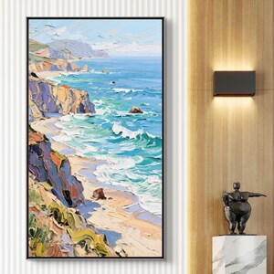 Puede incluir: Pintura al &oacute;leo de un paisaje costero en un marco negro. La obra representa una escena vibrante del oc&eacute;ano encontr&aacute;ndose con la costa, con acantilados y olas en tonos de azul, verde, amarillo y morado. La pintura se exhibe en una pared.