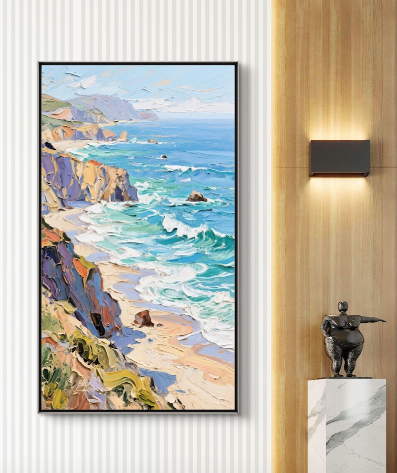 Puede incluir: Pintura al &oacute;leo de un paisaje costero en un marco negro. La obra representa una escena vibrante del oc&eacute;ano encontr&aacute;ndose con la costa, con acantilados y olas en tonos de azul, verde, amarillo y morado. La pintura se exhibe en una pared.