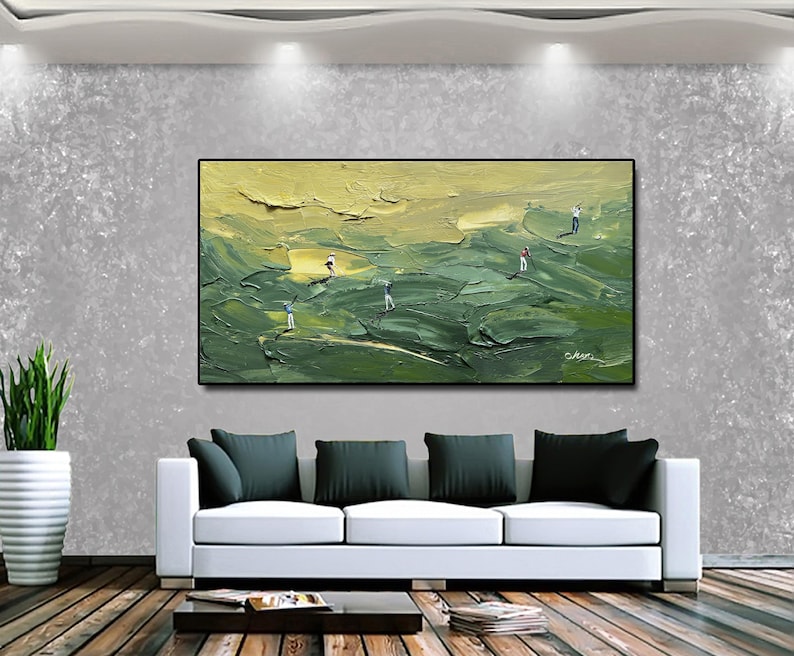 Op de afbeelding: Een olieverfschilderij dat een golfbaan met verschillende golfers afbeeldt. Het kunstwerk heeft een textuur, impasto-stijl met groen- en geeltinten. Het schilderij is zwart omlijst en hangt boven een witte bank met donkergroene kussens.
