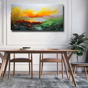 K&ouml;nnte beinhalten: Ein Gem&auml;lde, das einen Sonnenuntergang &uuml;ber einem See mit einem kleinen Baum im Vordergrund zeigt. Der Himmel ist eine Mischung aus Orange, Gelb und Rosa, und das Wasser ist tiefblau. Das Gem&auml;lde ist in einem realistischen Stil ausgef&uuml;hrt.