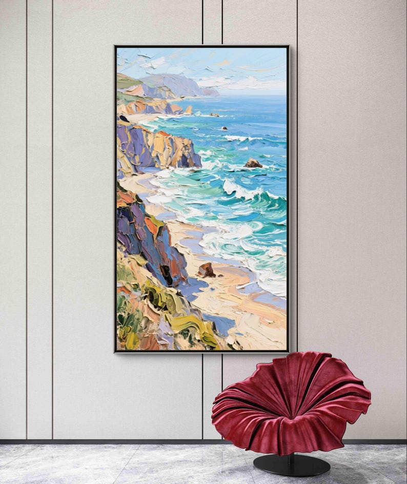 Puede incluir: Pintura al &oacute;leo de un paisaje costero. La obra representa una playa con olas turquesas rompiendo en la orilla. Acantilados con tonos morados, naranjas y verdes bordean la playa. La pintura est&aacute; enmarcada en negro y cuelga de una pared blanca.