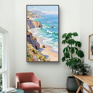 Puede incluir: Una pintura al &oacute;leo de un paisaje costero con acantilados, una playa y olas del oc&eacute;ano. La obra de arte tiene un marco negro y se exhibe en una pared blanca. La paleta de colores incluye azules, verdes, amarillos y marrones, creando una escena vibrante y texturizada.