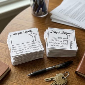 May include: Two stacks of white square paper cards with black printed text and a cross graphic. The left stack features a blank space for writing, while the right stack displays Psalm 145:18. Both cards include the text Prayer Request and He hears you.