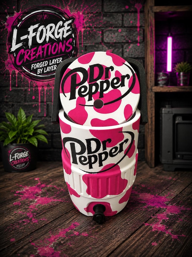 Pu&ograve; includere: Un refrigeratore per bevande bianco e rosa acceso con stampa a macchie di mucca, caratterizzato dal logo nero Dr Pepper sulla parte anteriore e sul coperchio. Il refrigeratore cilindrico ha una maniglia nera e un rubinetto nero alla base.