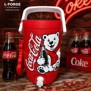 May include: A red cylindrical beverage cooler featuring a white handle and a graphic of a white polar bear wearing a red scarf and holding a Coca-Cola bottle. The cooler has a white spigot at the base and the Coca-Cola logo printed on the side.