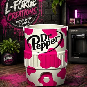 Pu&ograve; includere: Un refrigeratore cilindrico bianco caratterizzato da un vivace motivo a macchie di mucca rosa e dal logo nero Dr Pepper stampato sul davanti. Il refrigeratore presenta una fascia centrale testurizzata e un pulsante bianco circolare.