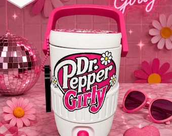 May include: A white beverage cooler with a pink handle and spigot, featuring a black and pink graphic that reads Dr. Pepper Girly surrounded by white daisy icons. The cooler has a ribbed base and a lid with a matching floral design.