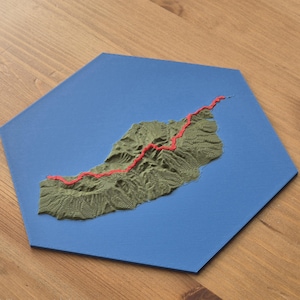 Könnte beinhalten: Eine 3D-topografische Karte einer Insel mit einem roten Pfad, auf einer blauen sechseckigen Basis. Die Insel ist in Grün- und Brauntönen strukturiert, wobei sich der rote Pfad über ihre Oberfläche schlängelt. Die Basis hat eine einfarbige blaue Farbe.