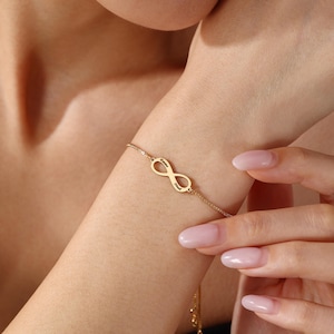 Puede incluir: Una pulsera de tono dorado con un símbolo de infinito como dije central. Los nombres Emma y Noah están grabados en los bucles del símbolo. La pulsera está formada por una cadena fina que se conecta al símbolo de infinito por ambos lados.