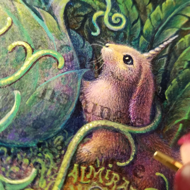 May include: A close-up of a pink and purple rabbit with a single horn, surrounded by green leaves and vines. The rabbit is looking up and has a curious expression. The word "ALMIRAS" is visible in the lower right corner of the image.
