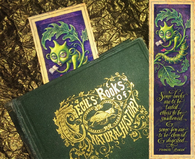 May include: A green book with gold lettering that reads "Cecil's Books of Natural History". A bookmark with a green creature reading a book is tucked into the book. The bookmark has a quote from Francis Bacon that reads "Some books are to be tasted, others to be swallowed, and some few are to be chewed and digested."