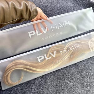 Puede incluir: Dos bolsas de almacenamiento rectangulares de plástico esmerilado semitransparente con cremalleras blancas. Cada bolsa tiene el texto impreso en blanco PLV HAIR SLOVENIA. Una bolsa contiene extensiones de cabello rubio claro.