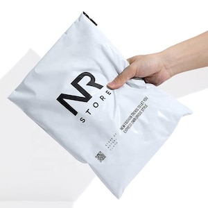 Könnte beinhalten: Ein weißer, rechteckiger Versandbeutel aus Kunststoff mit schwarzem Aufdruck. Der Beutel zeigt das Logo NR STORE, den Text NEW FASHION TRENDS TO LET YOU EXPRESS OWN UNIQUE STYLE, den Text STORE OF ACTUAL CLOTH und einen kleinen quadratischen QR-Code.