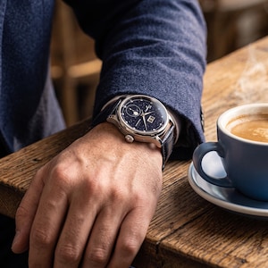 May include: A wristwatch with a dark blue, starry night-themed dial featuring a moon phase complication, a date window, and silver-toned hands. The watch has a polished silver-toned metal case and a dark blue leather strap with a textured finish.