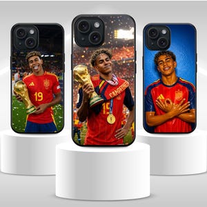 Peut inclure: Trois coques de smartphone noires représentant un joueur de football portant le maillot rouge et bleu de l'équipe nationale espagnole. Le joueur tient un trophée doré sur deux coques et pose les mains sur la poitrine sur la troisième.