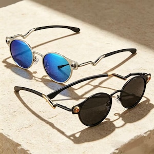 May include: Two pairs of round-frame sunglasses. The top pair features a silver-tone metal frame with reflective blue lenses and black temples. The bottom pair has a black frame with dark lenses, gold-tone accents, and black temples.