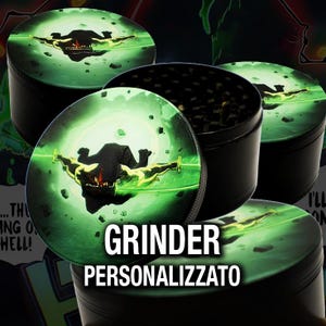 Puede incluir: Un molinillo de hierbas cilíndrico negro con una tapa circular que muestra una ilustración gráfica de una criatura oscura empuñando una espada verde brillante sobre un fondo verde claro. El molinillo tiene un borde texturizado y base negra.