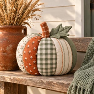 May include: A fabric pumpkin decoration featuring alternating vertical panels of various patterns including a green and white gingham check, a rust orange floral print, a cream and green striped fabric, and a solid olive green fabric with a leaf.