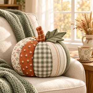 May include: A decorative fabric pumpkin featuring alternating vertical panels of various patterns including a green and white gingham check, a rust orange floral print, a cream floral print, and a cream fabric with thin orange and green stripes.
