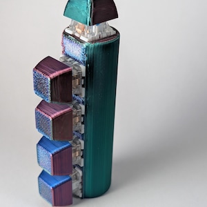 May include: A vertical mechanical keyboard macro pad featuring a cylindrical teal body with five individual keys. Each keycap displays a shifting iridescent finish that transitions between shades of purple, blue, and green, mounted on clear switches.