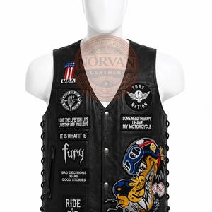 Op de afbeelding: Een zwart leren vest met meerdere patches, waaronder een Amerikaanse vlag, een schedel-embleem en teksten zoals "Love the life you live", "Fury Nation", "Some need therapy I have my motorcycle", "It is what it is" en "Ride or die".