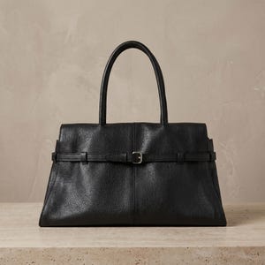 Front view of a textured black large office handbag in genuine leather, showing the signature horizontal belt strap with silver buckle and clean east-west structured silhouette.