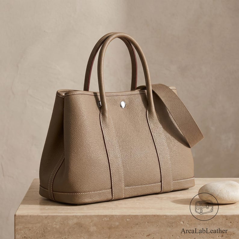 Khaki full grain leather tote bag for women with rolled top handles, contrast saddle stitching and removable crossbody strap, shown front-on against a clean studio background.