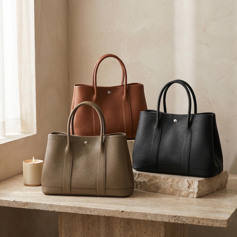 Group shot of the handmade leather tote bag in all three colors — khaki, black and brown — lined up to show the full grain cowhide shades and color options.