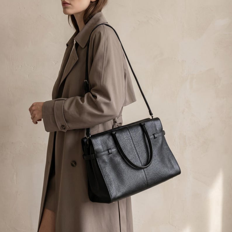 Lifestyle shot of the black leather office handbag worn crossbody with its adjustable strap, showing how the everyday genuine leather purse fits a hands-free workday commute.