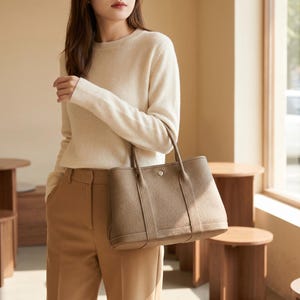 Woman carrying the khaki leather tote bag as a shoulder bag while walking, styling the minimalist cowhide purse as an everyday work and commuter handbag.