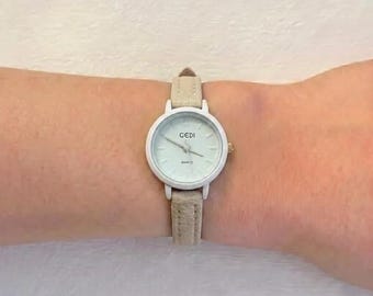 Orologio da polso al quarzo da donna con cassa rotonda bianca e cinturino in pelle beige.