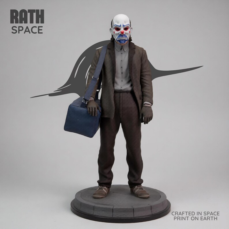May include: A detailed statue of a figure in a clown mask, wearing a brown suit, gray shirt, and carrying a blue bag. The statue stands on a gray circular base. The text "RATH SPACE" and "CRAFTED IN SPACE PRINT ON EARTH" are visible.