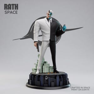 May include: A Two-Face statue, a DC Comics villain, stands on a cityscape base with stacks of money. The figure is split down the middle, with one side in a white suit and the other in a black suit. The statue holds a gun and a coin.
