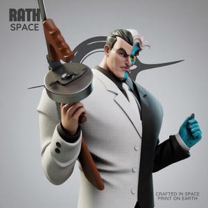 May include: A detailed statue of the DC Comics villain Two-Face, split down the middle with one side in a white suit and the other in a black suit. He holds a Tommy gun and a small object. The text "RATH SPACE" is visible.
