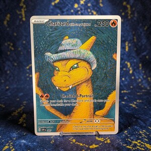 Op de afbeelding: Een Charizard with Grey Felt Hat ruilkaart met een geel draakachtig wezen dat een grijze hoed met textuur draagt tegen een blauwe, wervelende achtergrond. De kaart toont 250 HP, de tekst Charizard-Portrait en details over de spelvaardigheden.