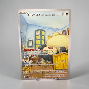 Op de afbeelding: Een Snorlax with Munchlax & Mew ruilkaart met 150 HP. De illustratie toont een grote Snorlax die in een houten bed in een kamer slaapt, terwijl een Munchlax op een stoel zit. De tekst bevat Ability Voraciousness en de aanval Thudding Press.