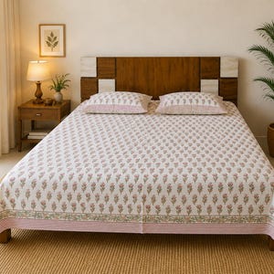 May include: A white cotton bed sheet and two matching pillowcases featuring a repeating pattern of small pink flowers with green stems and leaves, finished with a decorative border of pink stripes and green floral vines along the edges.