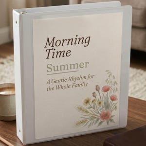 May include: A white three-ring binder with a cream-colored cover insert featuring the text Morning Time Summer A Gentle Rhythm for the Whole Family and a watercolor illustration of wildflowers including poppies, wheat, and green foliage.
