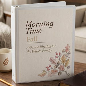 Könnte beinhalten: Ein weißer Ringordner mit cremefarbenem Einband, der den Text Morning Time Fall A Gentle Rhythm for the Whole Family sowie eine Aquarellillustration von Herbstblättern, Beeren und Eicheln in der unteren rechten Ecke zeigt.