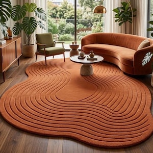 Peut inclure: Un tapis de forme organique irrégulière d'une couleur orange brûlé unie, présentant un motif texturé de lignes ondulées concentriques en relief qui imitent les contours topographiques, couvrant une grande partie du parquet en bois sombre.