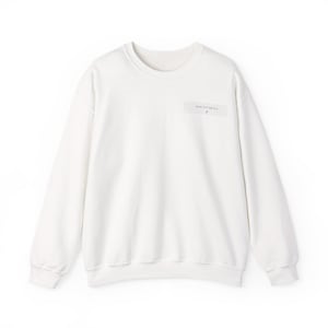 Op de afbeelding: Een wit sweatshirt met lange mouwen en een ronde hals, voorzien van een kleine rechthoekige patch op de linkerborst. De patch bevat de tekst "SAGITTARIUS" in zwarte hoofdletters met een klein sterrenbeeld-symbool direct onder het woord.
