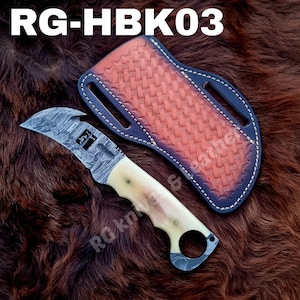 Op de afbeelding: Een vaststaand mes met een damaststalen lemmet met een haak en een lichtgekleurd botten handvat met een vingerring. Het mes wordt vergezeld door een bruine lederen schede met een vlechtpatroon en witte stiksels. Tekst luidt RG-HBK03.