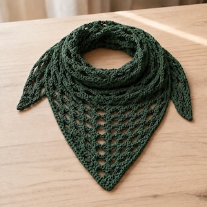 Puede incluir: Un pañuelo triangular de color verde bosque oscuro que presenta un patrón de ganchillo calado con un diseño de malla en forma de diamante repetitivo. El accesorio tiene un borde inferior puntiagudo y una construcción texturizada y anudada.