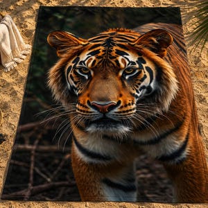 Peut inclure: Une serviette de plage rectangulaire présentant une impression photographique haute résolution en couleur du visage et du haut du corps d'un tigre. Le tigre a une fourrure orange avec des rayures noires, des accents blancs et des yeux ambrés.