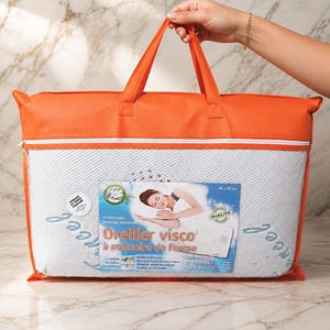 May include: A rectangular memory foam pillow packaged in a clear plastic bag with orange fabric trim and handles. The label features the text Oreiller visco &agrave; m&eacute;moire de forme, 40 x 60 cm, and an illustration of a person sleeping on a pillow.