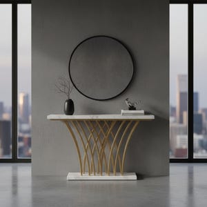 May include: A console table featuring a white marble top and base with a gold-toned metal frame composed of curved, intersecting vertical supports. A round mirror with a thin black frame is mounted on the wall above the table.