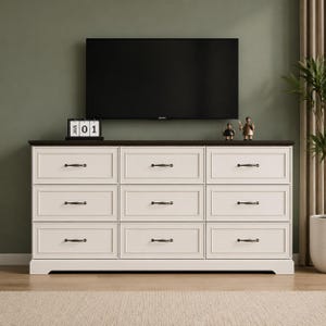 May include: A white nine-drawer dresser with a dark brown top surface. The dresser features three columns of three drawers, each equipped with dark metal handles. A black calendar block displaying JAN 01 sits on the left side of the top surface.